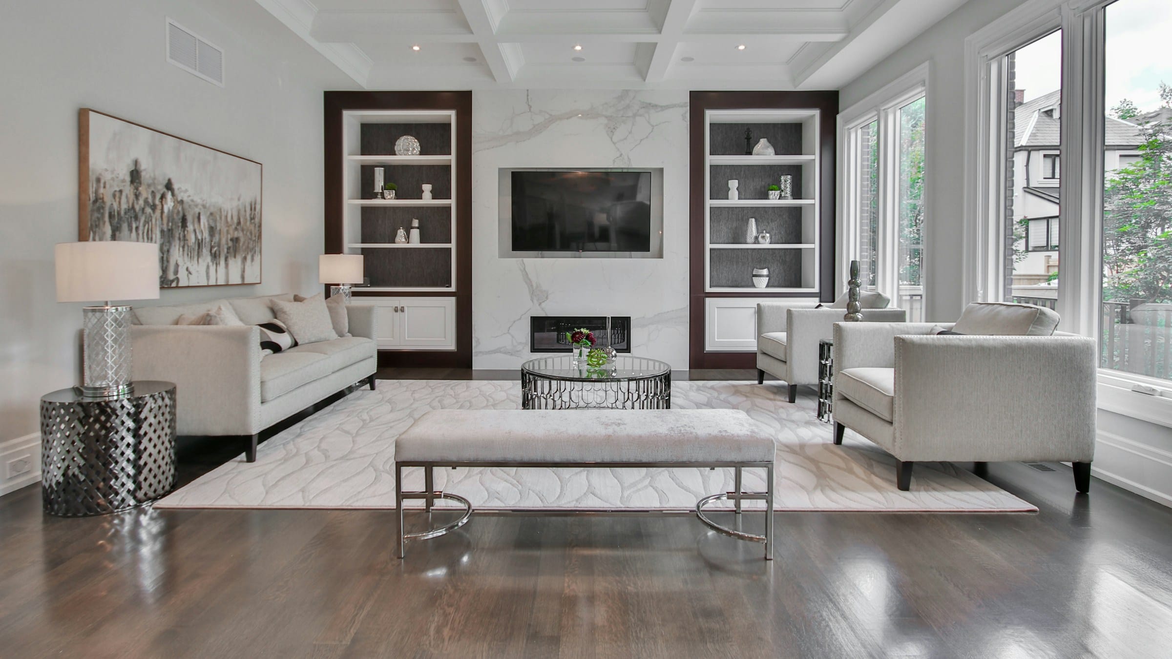 A formal living room with a coffered ceiling, built-in shelving and tall windows