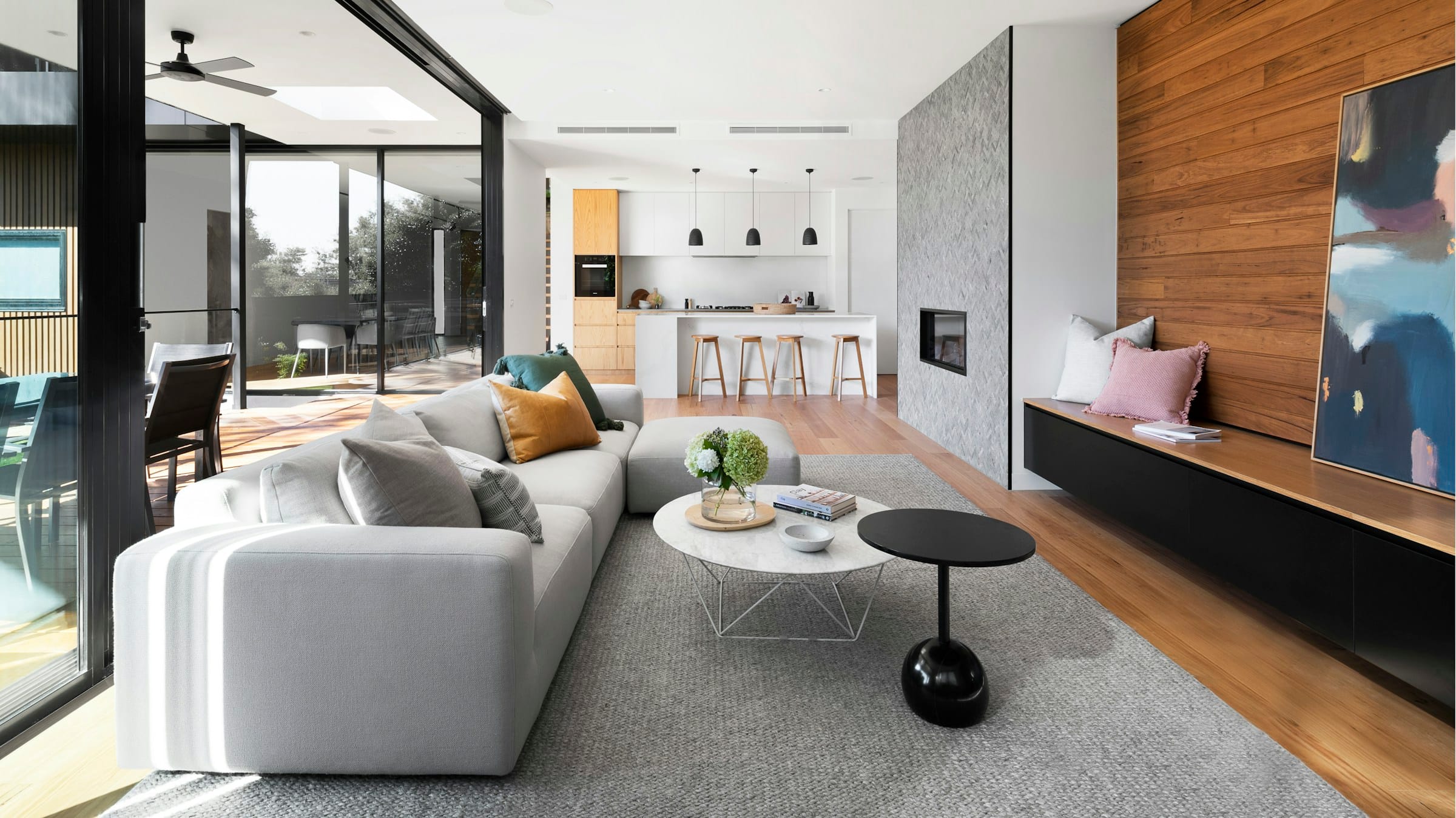 An open-plan living space with a full-height walnut panel wall behind the television